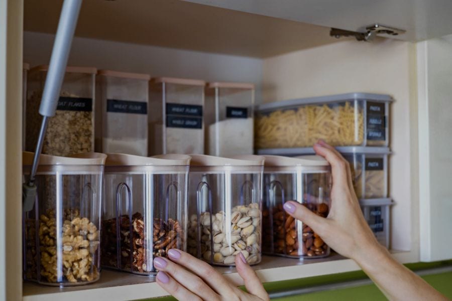 Modern kitchen larder with dry grains, pasta, and baking ingredients stored safely in airtight glass containers with silicone seals.